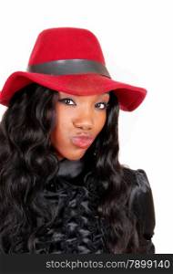 A closeup picture of a lovely African American woman in a black blouseand red hat and curly hair blowing a kiss, isolated for white background.
