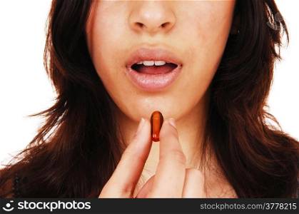 A closeup picture of the face on a young woman with an open mouthtaking a vitamin capsule, isolated on white background.