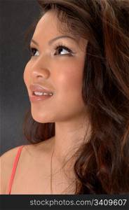 A closeup portrait of a young beautiful Asian woman, looking up, onlight gray background.
