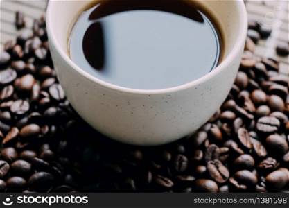 A closeup shot of a cup of coffee with coffee beans