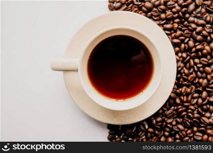 A closeup shot of a cup of coffee with coffee beans on a white background