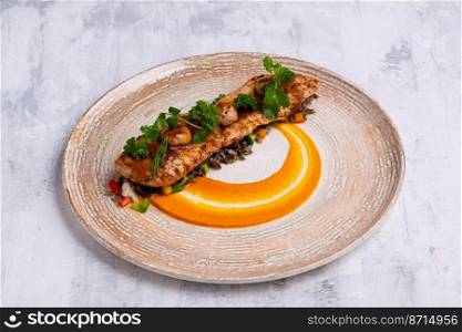 A closeup shot of a Fish course with salmon meat, herbs and orange sauce on a marble plate. Closeup shot of a Fish course with salmon meat, herbs and orange sauce on a marble plate