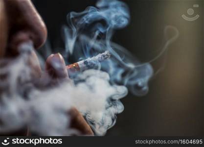 a closeup shot of a person puffing on a cigarette surrounded with smoke. Closeup shot of a person puffing on a cigarette surrounded with smoke