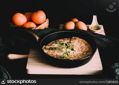 A closeup shot of an omelet in a roaster, fresh eggs, and tomatoes