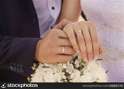 A closeup shot of newlyweds holding hands and showing the wedding rings. Closeup shot of newlyweds holding hands and showing the wedding rings