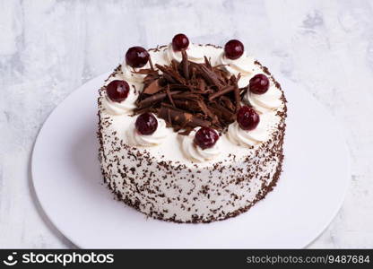 A closeup shot of white cream on Black Forest gateau cake with cherries on white marble surface. Closeup shot of white cream on Black Forest gateau cake with cherries on white marble surface