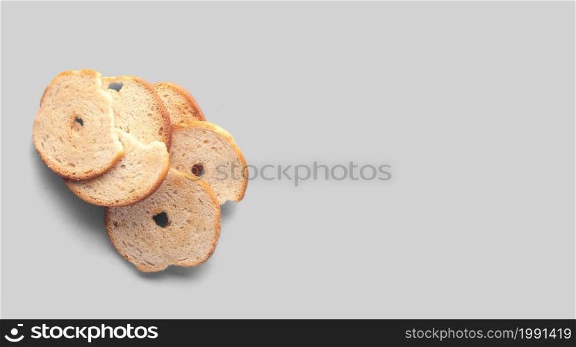 A closeup view of dry bread slices under the lights isolated on a grey background.