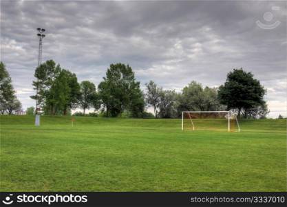 A cloudy unoccupied soccer field with trees in the background. (HDR photograph). Cloudy Soccer Field