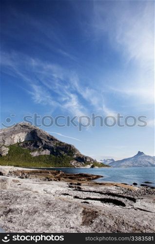 A coastal landscape in northern norway with a mountain and rock