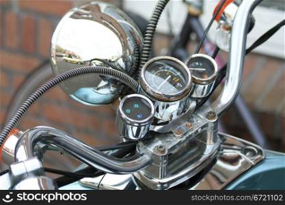 A cockpit of a vintage motorbike with chroom and rusty details