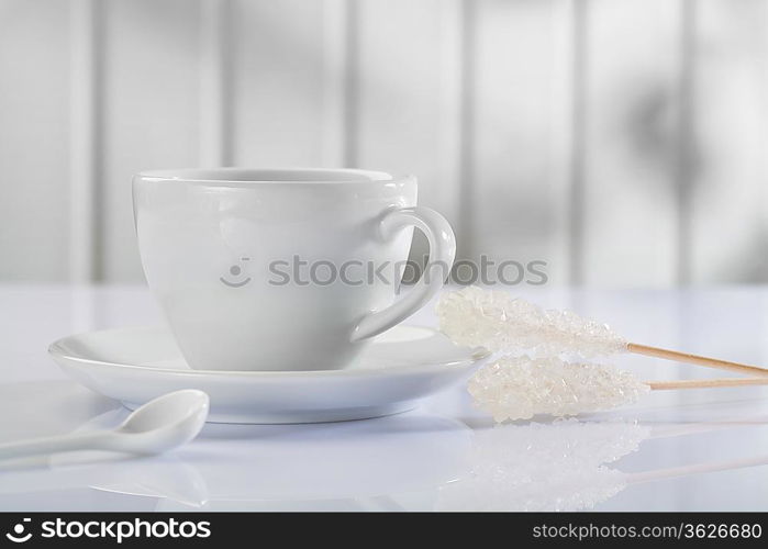 a coffee cup with spoon and sugar stick on white table