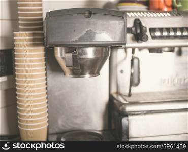 A coffee machine with a large stack of paper cups next to it