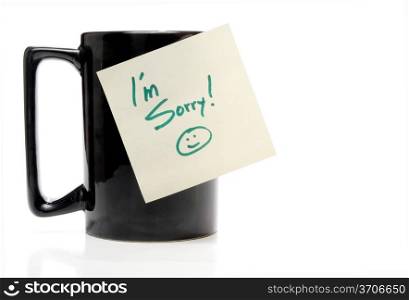 A coffee mug with an Im Sorry note.