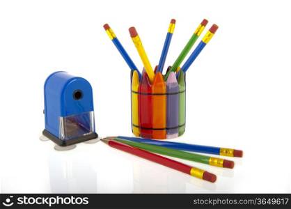 A collage of colourfull pencils in a cup with a blue pencil sharpener isolated over a white background