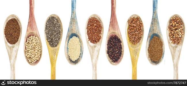 a collection of gluten free grains and seeds on isolated wooden spoons - kaniwa, sorghum, chia, amaranth,red quinoa, black quinoa, brown rice, teff, buckwheat (from left to right)