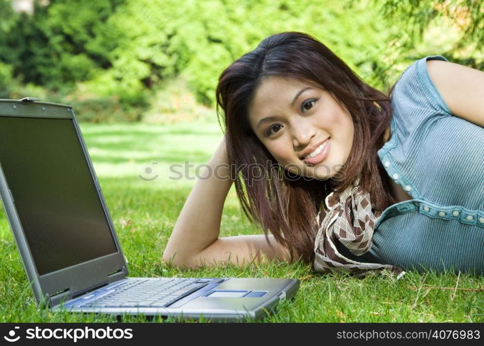 A college student bringing her laptop and relaxing in a park