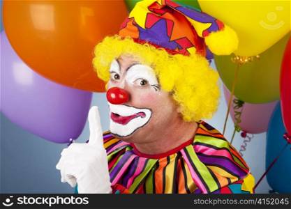 A colorful clown putting his finger to his lips so you will be quiet.