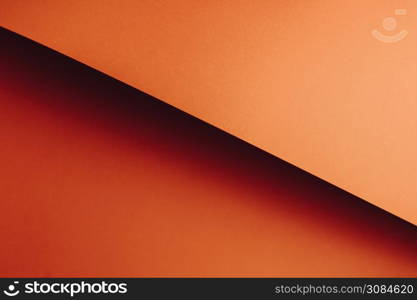 A colorful orange flat lay background with sharp layers and shadows with copy space