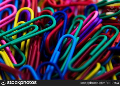 A colorful paper clip background. A variety of scattered colorful plastic paperclips