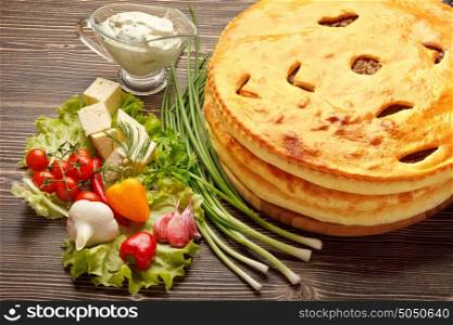 A colorful photo of traditional delicious beef osetinian pie. Heap of traditional Ossetian pies on wooden background.