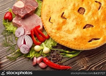 A colorful photo of traditional delicious beef osetinian pie. Fydzhin meat pie and vegetables on wood.