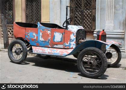 A colourful tattered open top vintage car in a street of Havana, Cuba.