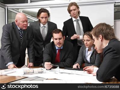 A company director and his staff, discussing plans, in a modern office cubicle