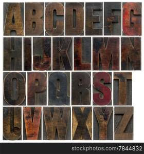 a complete English uppercase alphabet - a collage of 26 isolated antique wood letterpress printing blocks, stained by dark color inks