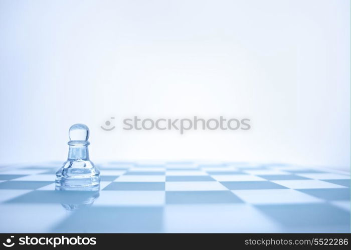 A conceptual photo of loenely glass pawn on the chessboard.