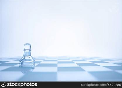 A conceptual photo of loenely glass pawn on the chessboard.