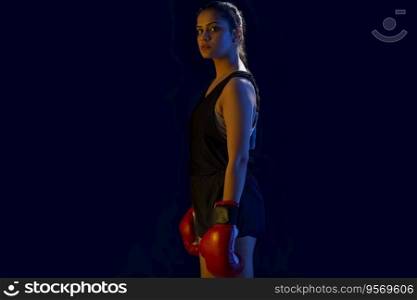 A CONFIDENT WOMAN BOXER STANDING AND LOOKING AT CAMERA