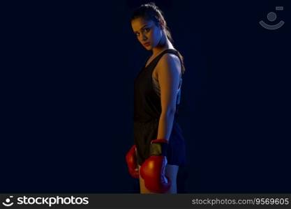 A CONFIDENT WOMAN BOXER STANDING IN FRONT OF CAMERA