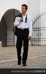 A confident young man coming home in the morning still dressed in the black tie outfit from the night out before