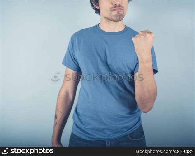 A confident young man wearing a blue t-shirt is doing a fist pump