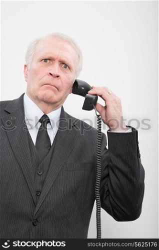 A confused businessman using a telephone