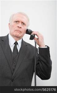 A confused businessman using a telephone