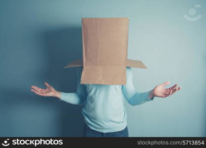 A confused man is standing with a cardboard box on his head