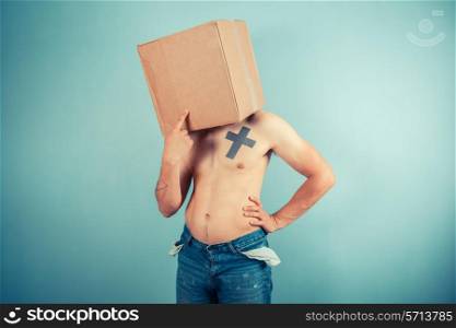 A confused young man is standing with a cardboard box on his head