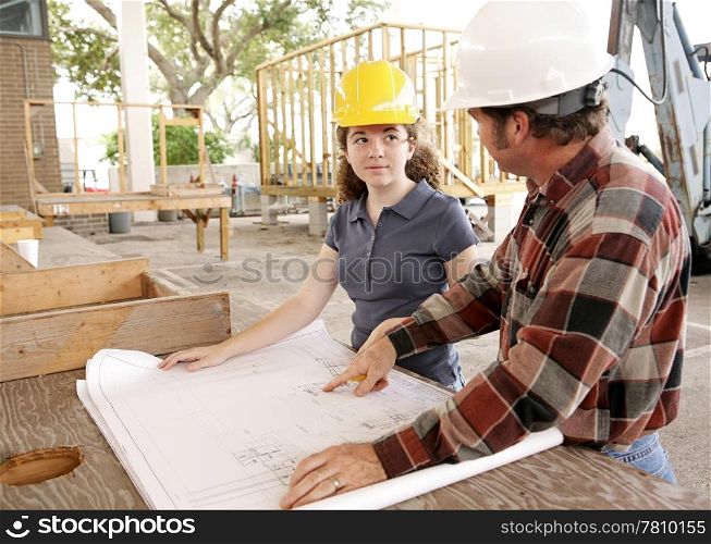 A construction apprentice listening as her foreman goes over the blueprints.