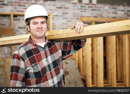 A construction day laborer carrying wood beams. Authentic construction worker on an actual construciton site.