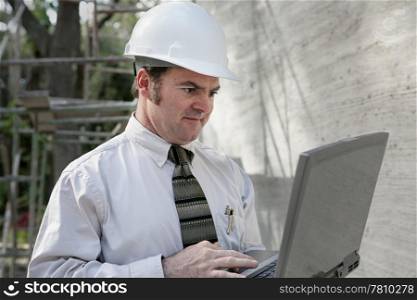A construction engineer using his laptop computer on the job site.