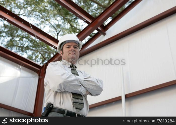 A construction inspector standing inside an unfinished steel frame building. `