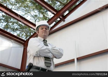 A construction inspector standing inside an unfinished steel frame building. `