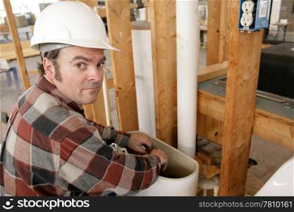 A construction plumber fixing a toilet on new building construction.