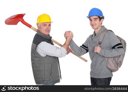 A construction worker and his apprentice shaking hands.