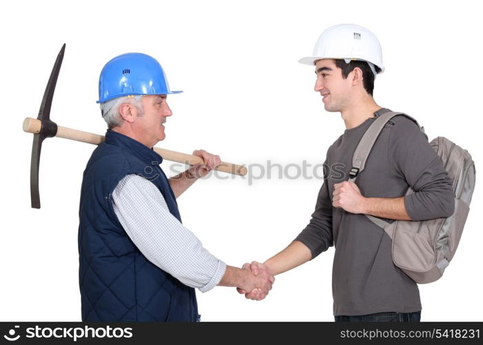 A construction worker and his trainee shaking hands.