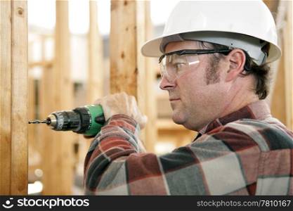 A construction worker drilling and wearing proper safety equipment according to OSHA regulations. Authentic and accurate content depiction.