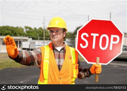 A construction worker holding a stop sign and directing traffic.