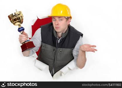 A construction worker holding a trophy cup.