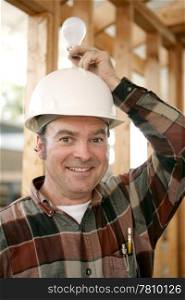 A construction worker in a hardhat holding a lightbulb over his head.
